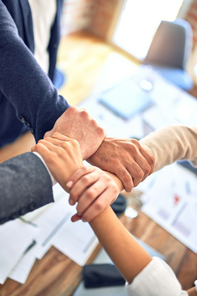Sales team members joining hands over a desk in an Irving, Texas office